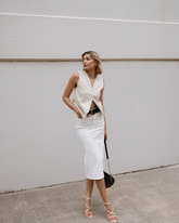 a lady wears a white suit vest with a white pencil midi skirt